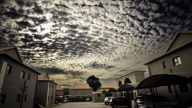 Two-storey townhouses and carports in a Gauteng complex under a cloudy sky